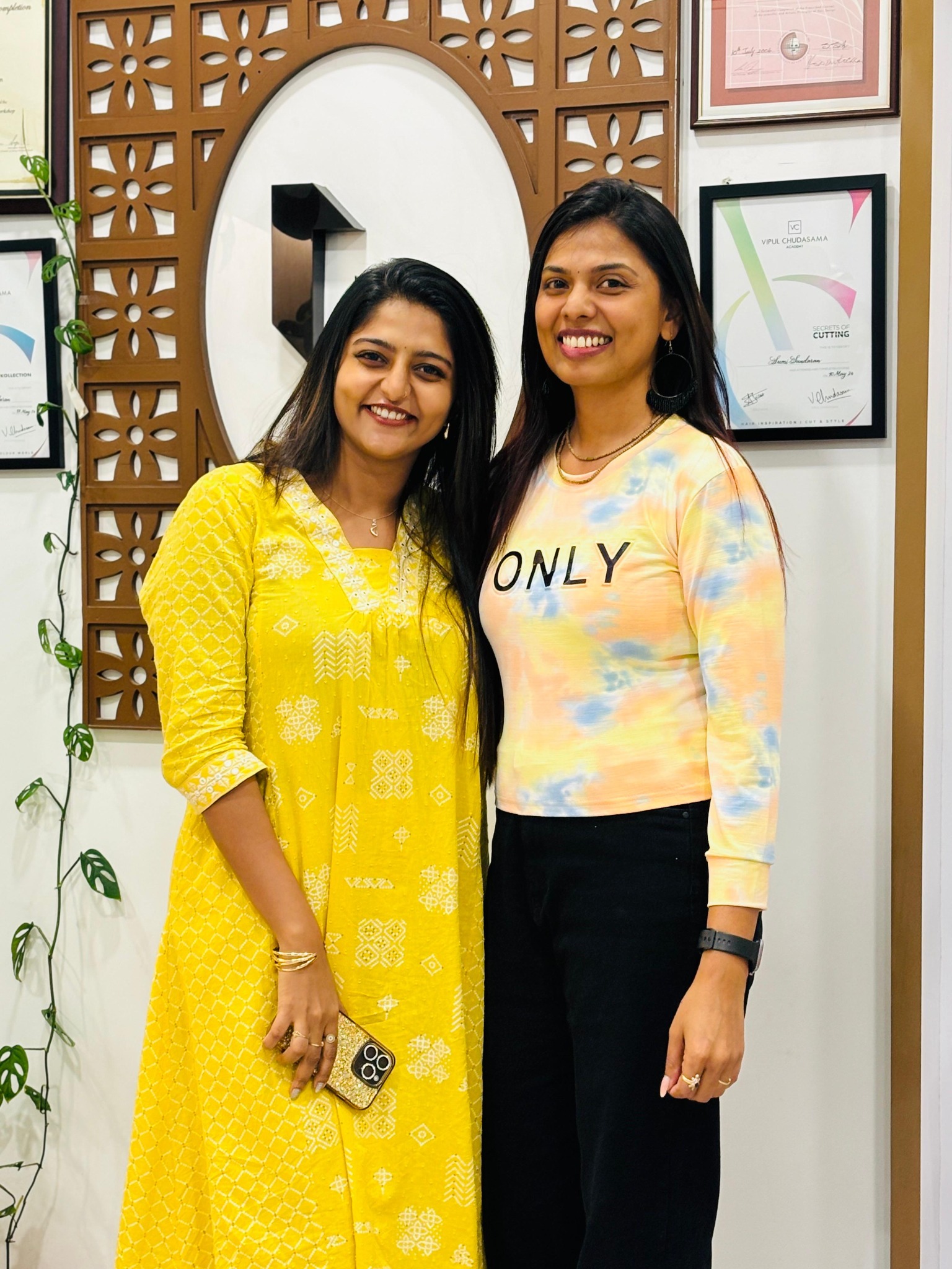 Two women in yellow and pastel outfits at the salon