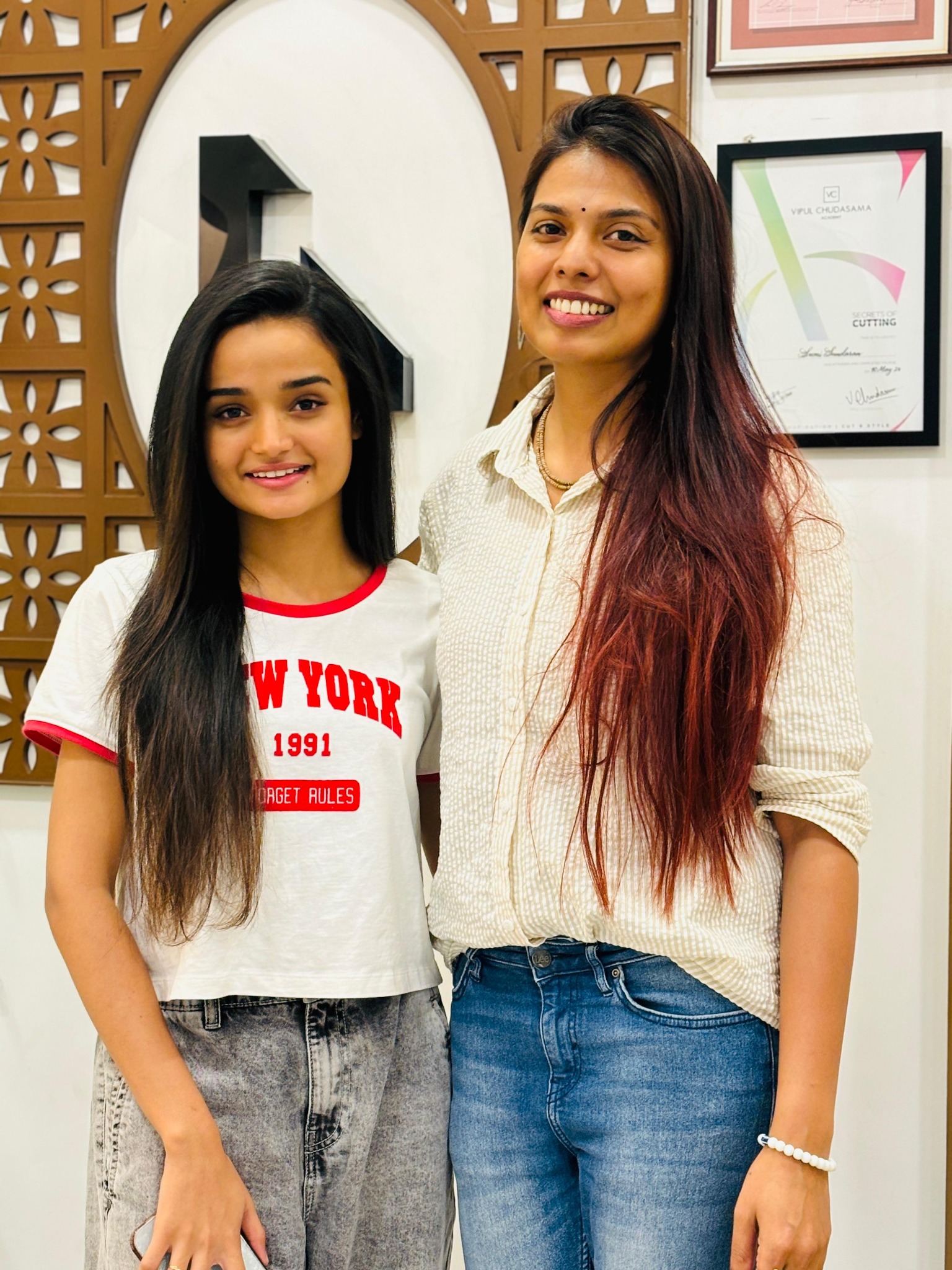 Two women with long styled hair posing inside the salon